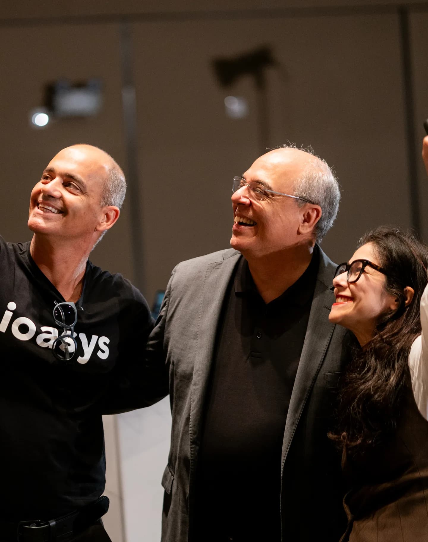 Três organizadores do AI Summit tirando uma selfie com o público