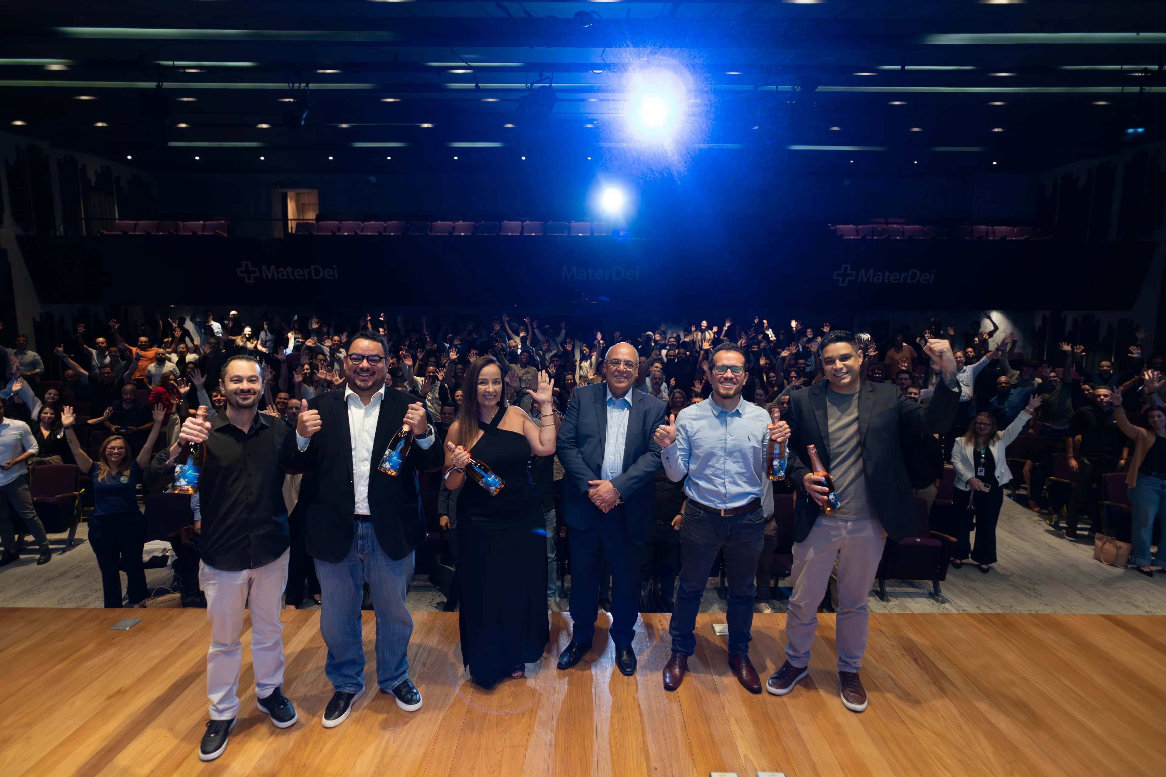 Equipe do AI Summit no palco, diante do público com as mãos erguidas