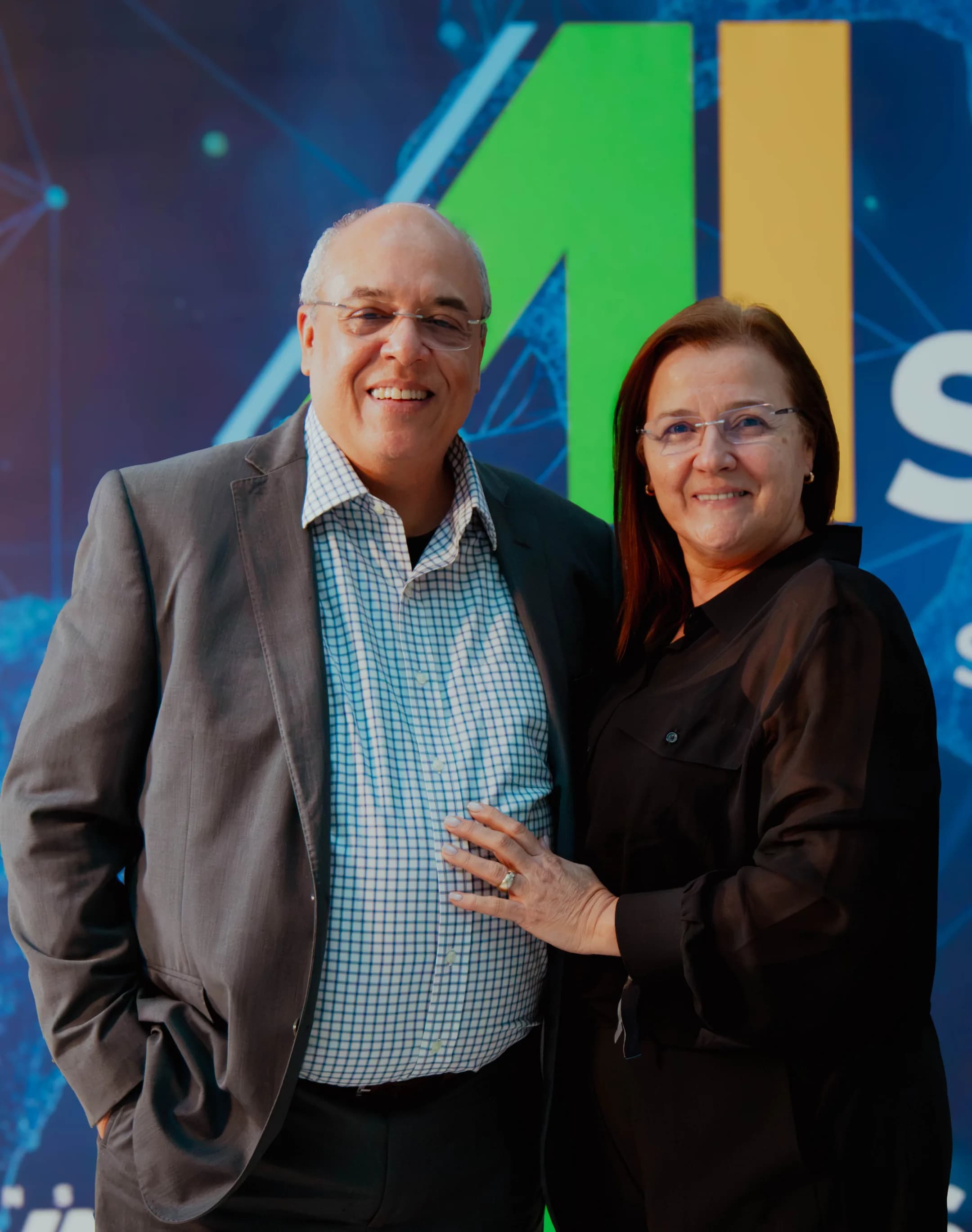 Duas pessoas posando diante do painel do AI Summit Brasil