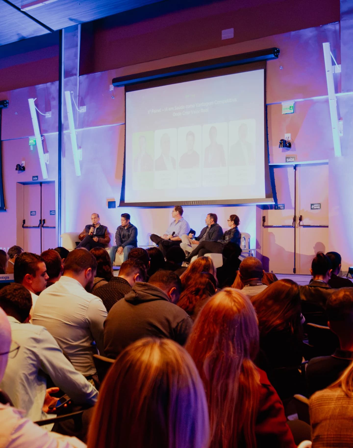 Plateia lotada acompanhando um painel no palco do AI Summit